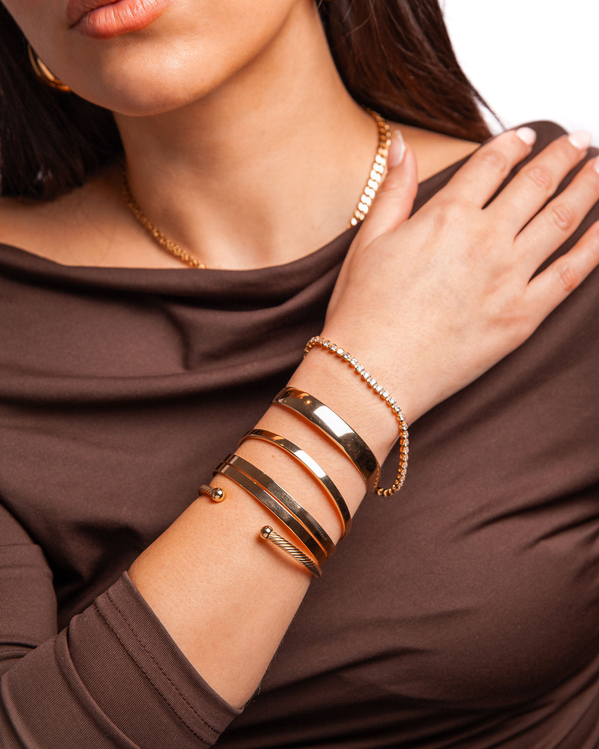 Stylish gold bangles and bracelet on a woman's wrist, elegant accessory collection.